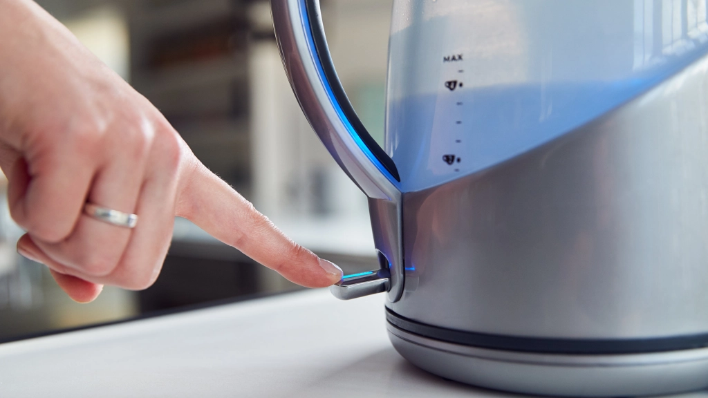 Close Up Of Woman Pressing Power Switch On Electric Kettle To Save Energy At Home, 