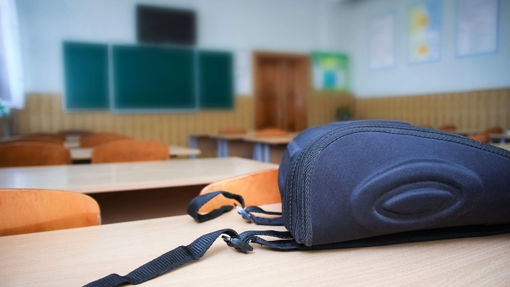A School backpack on the desk in the classroom against the backg, School backpack on the desk in the classroom against the background of the school board