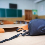 A School backpack on the desk in the classroom against the backg, School backpack on the desk in the classroom against the background of the school board