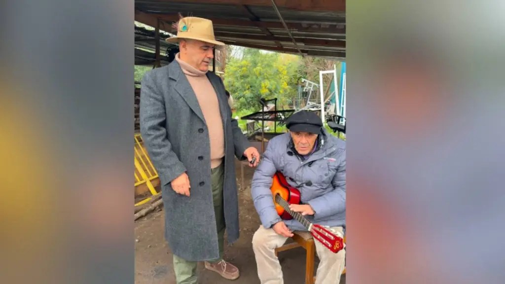 El alcalde Pablo Urrutia acompaña al histórico vecino quilaquino, quien hoy vuelve a sonreír y a compartir su talento con la guitarra tras ser rescatado del abandono., Municipalidad de Quilaco